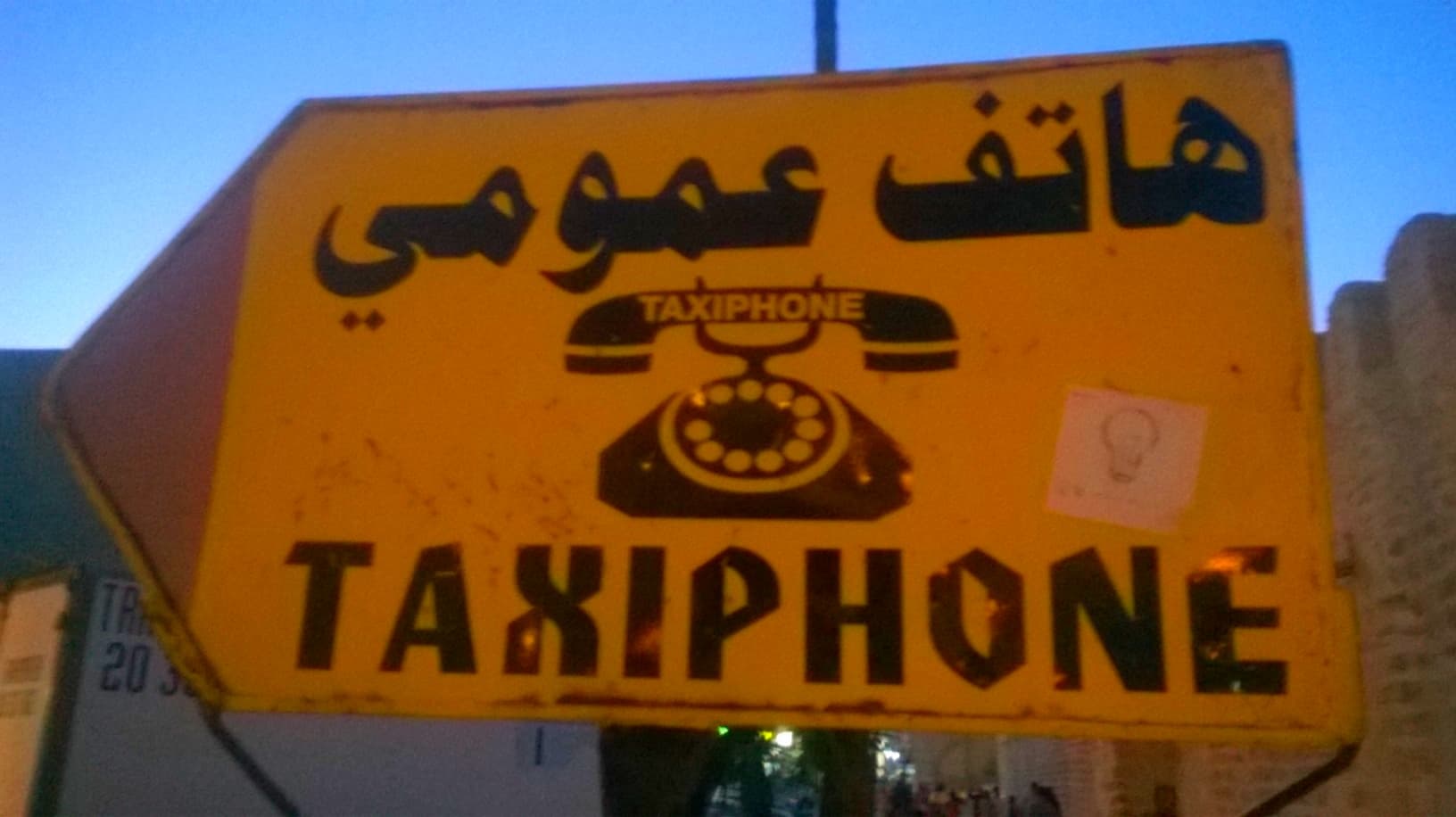 Un panneau jaune de taxiphone en arabe et en français